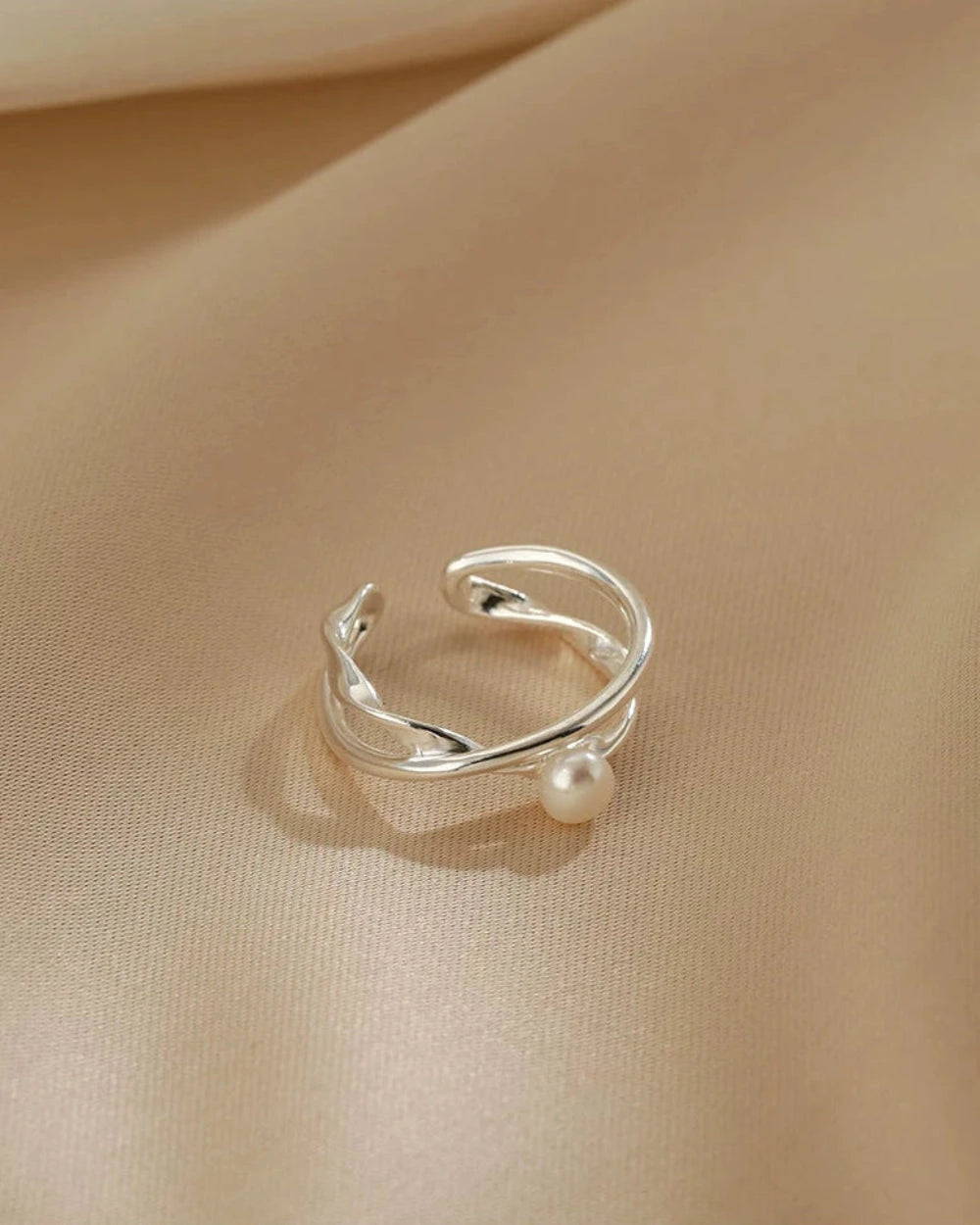 Silver ring with a pearl on a beige fabric background