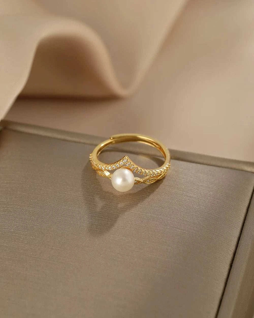 Gold ring with a pearl on a beige fabric background