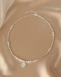 Pearl necklace with a silver pendant on a beige fabric background