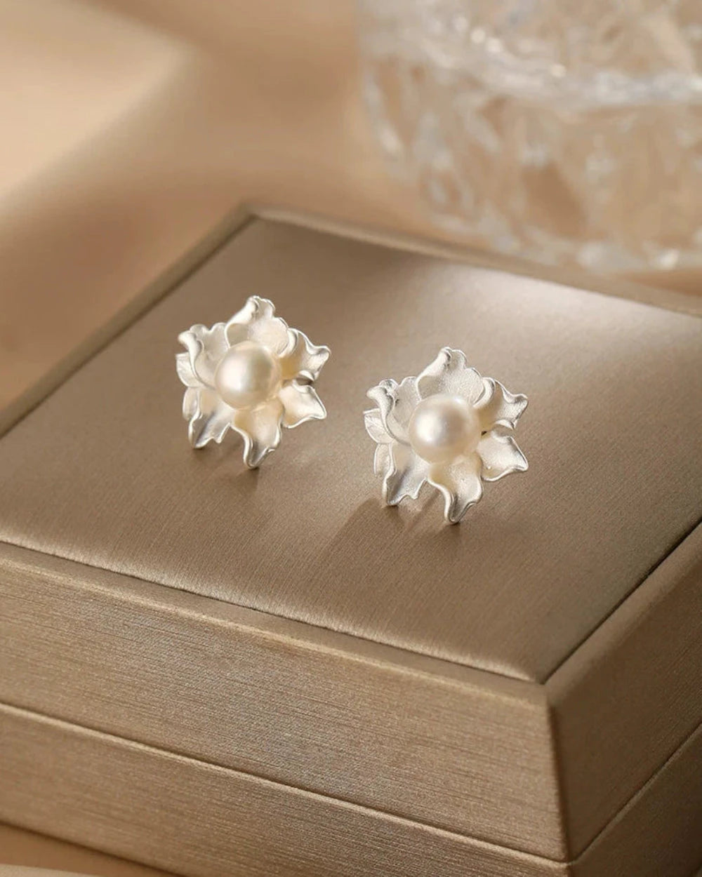 Pearl flower earrings on a beige jewelry box