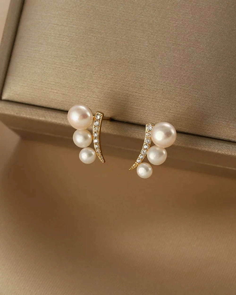 Pair of pearl earrings on a beige cushion