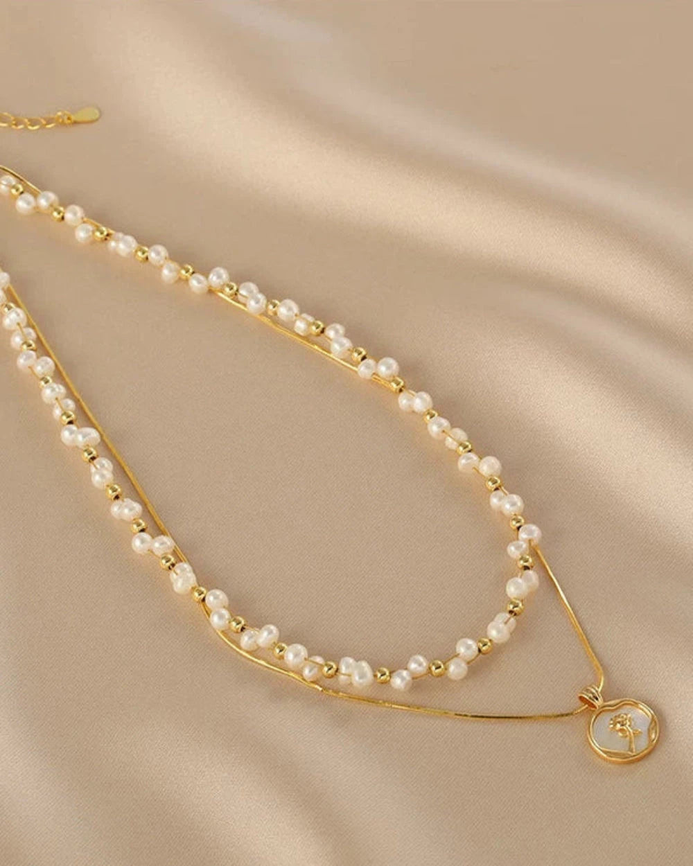 Gold necklace with pearl beads on a beige fabric background