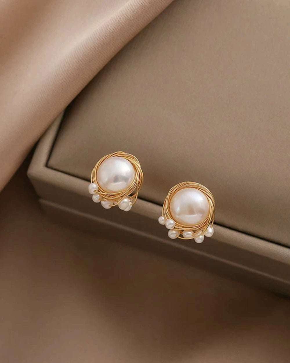 Pearl earrings with gold accents on a beige surface