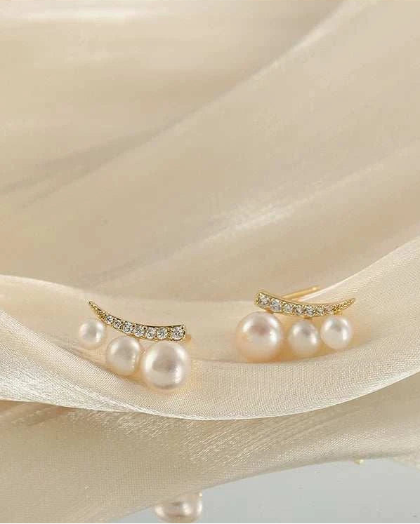 Pearl and crystal earrings on a beige fabric background