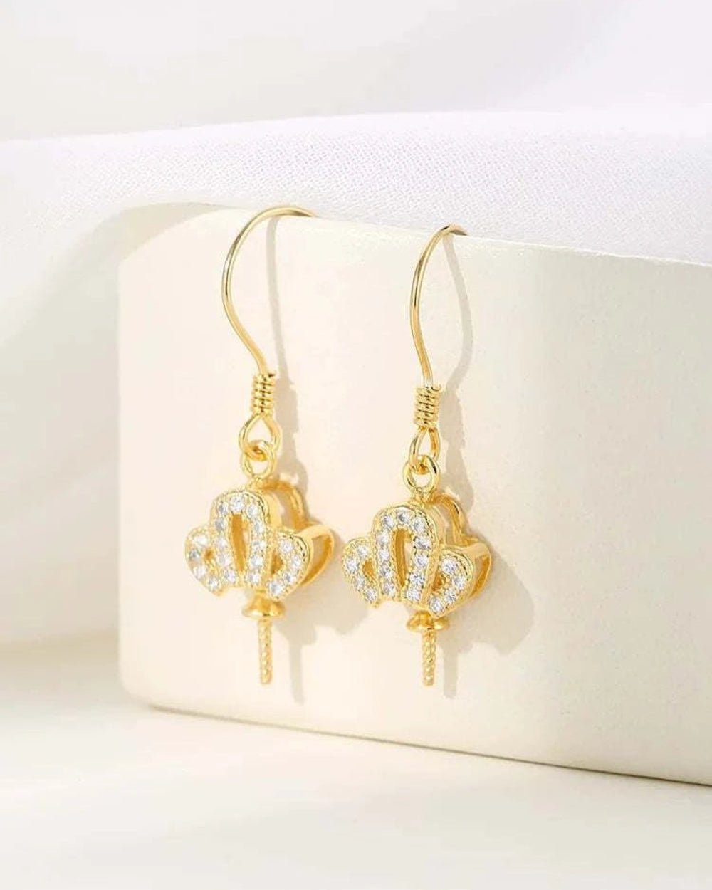 Gold earrings with heart designs on a white box