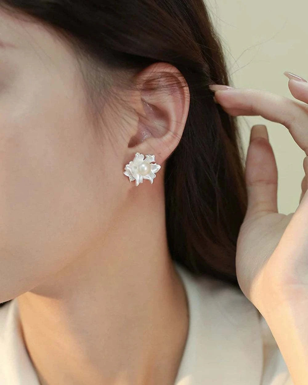 Close-up of a person wearing a silver flower-shaped earring.