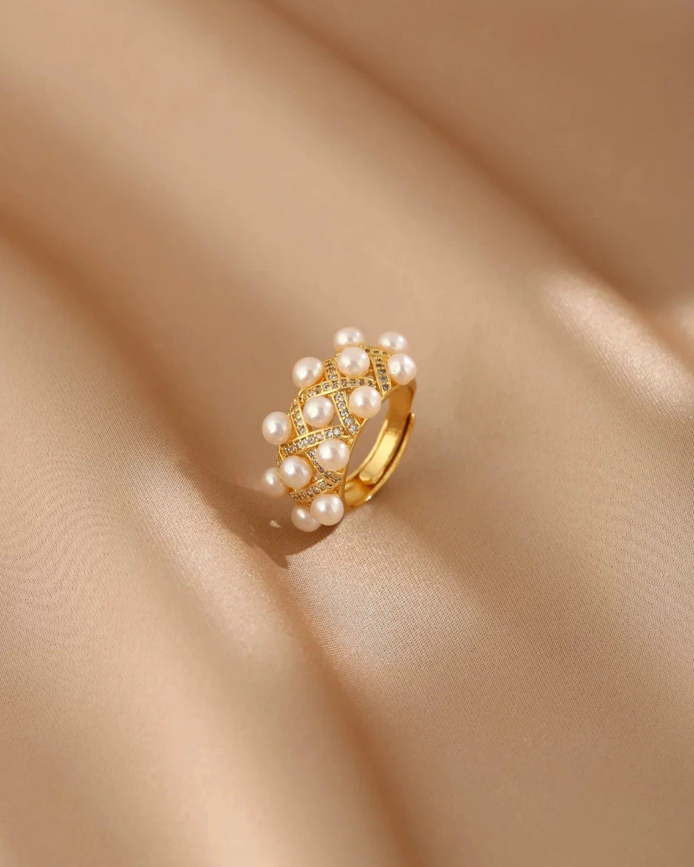 Gold ring with pearls on a beige fabric background