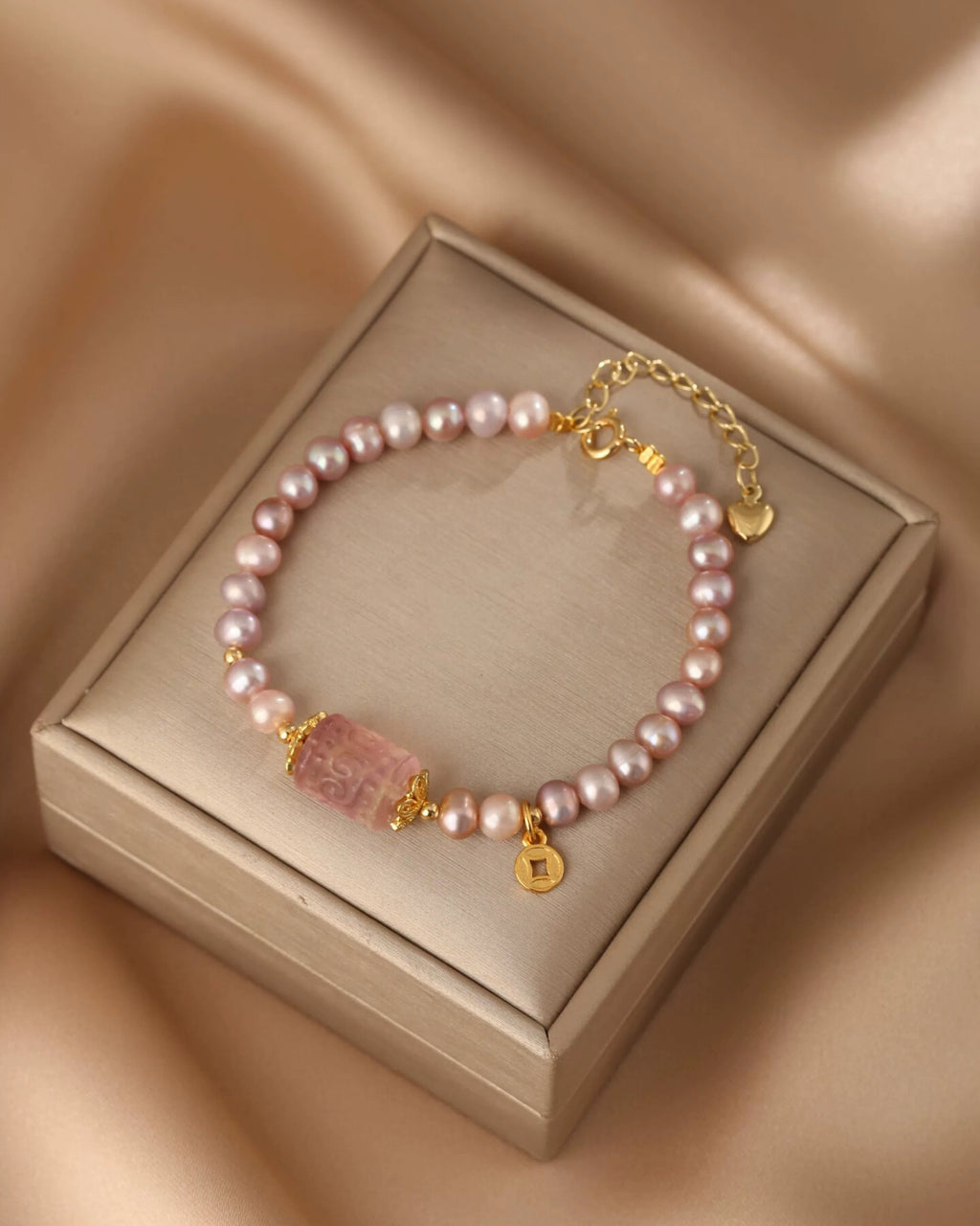 Pearl bracelet with gold accents on a beige box against a beige background
