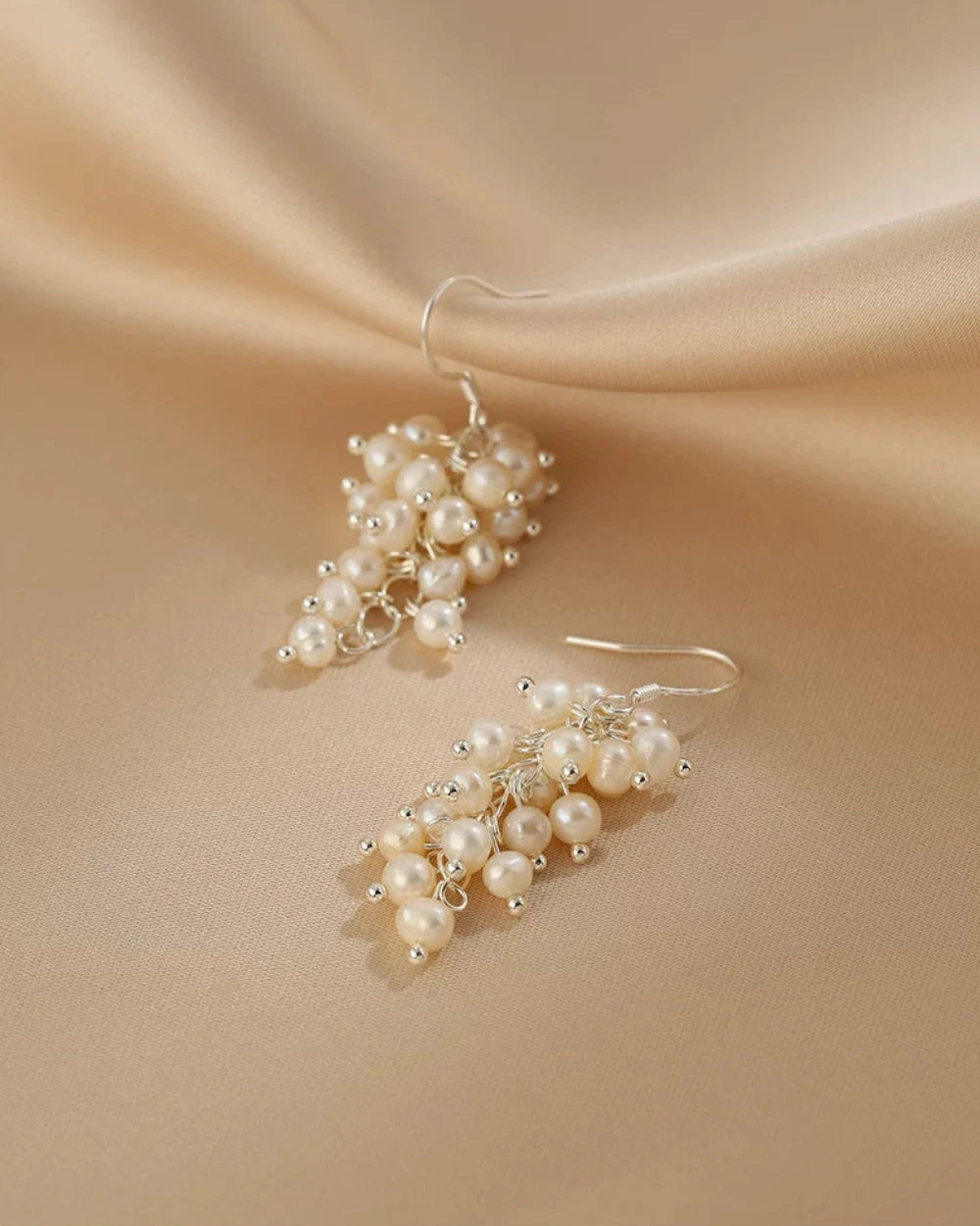 Pearl earrings on a beige fabric background