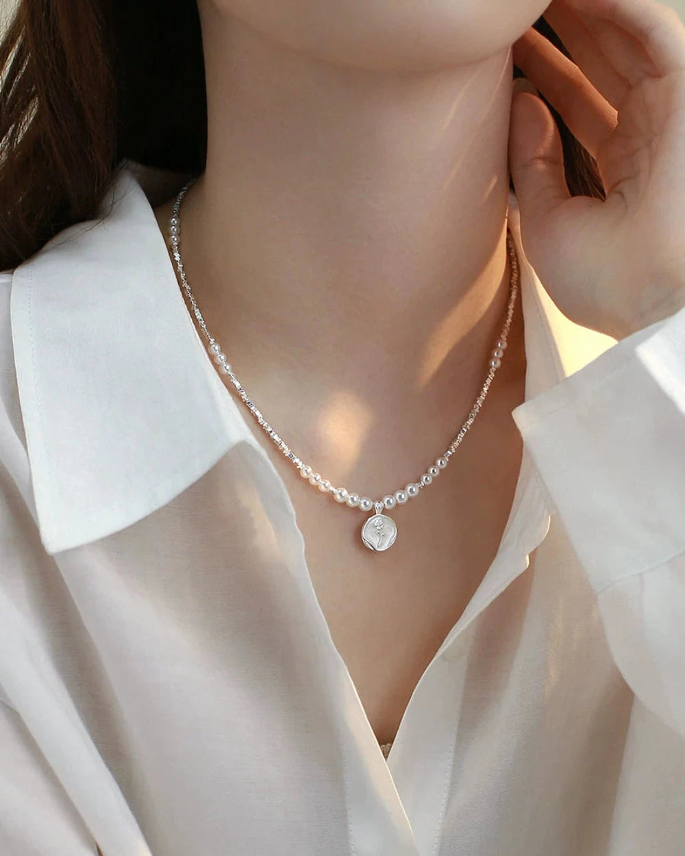 Pearl necklace being worn by a person in a white shirt