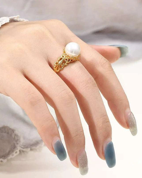 Gold ring with a pearl on a hand with gray nail polish