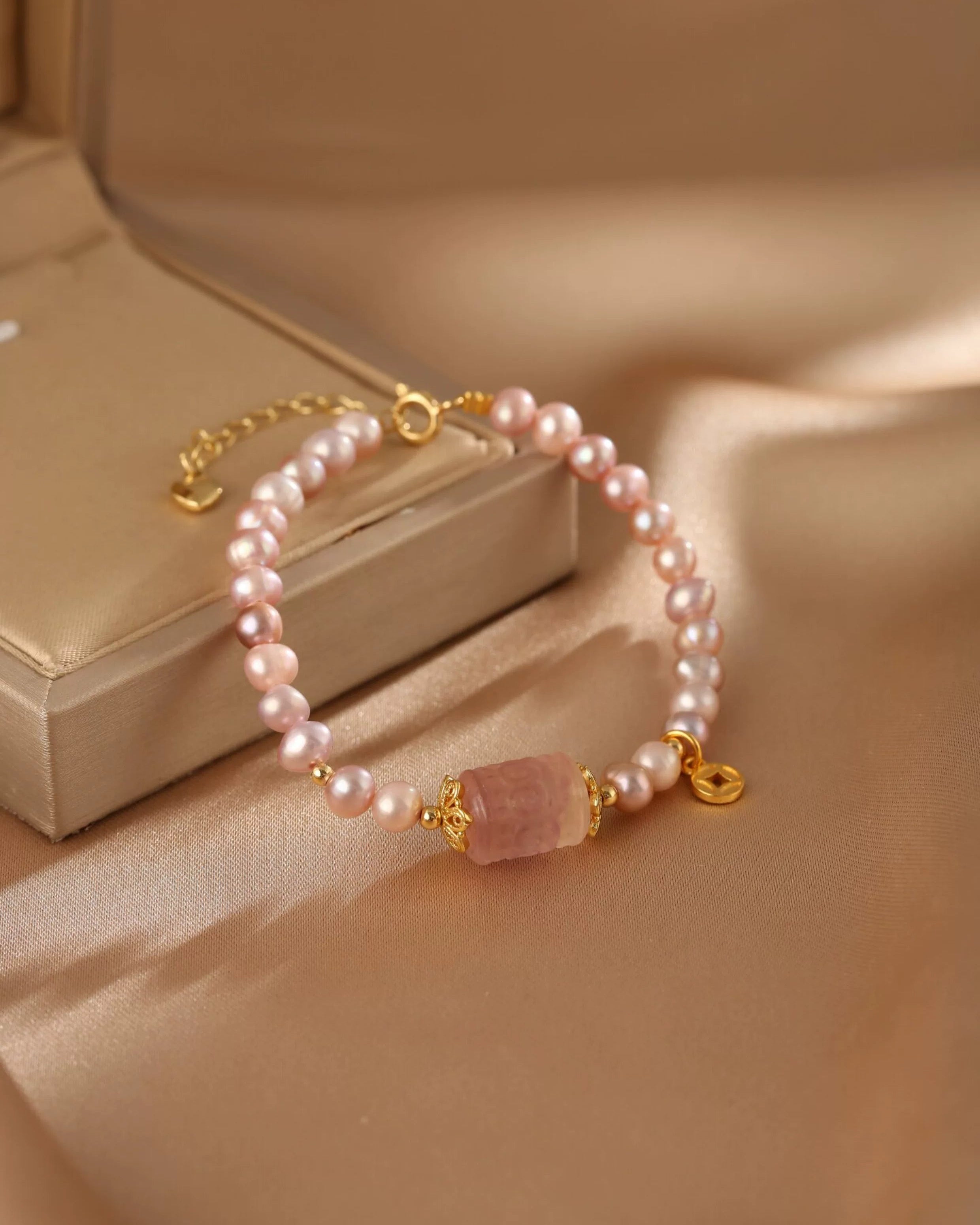 Pearl bracelet with a pink stone on a beige fabric background