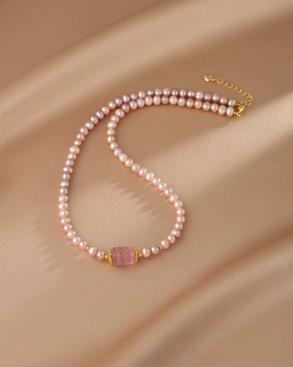 Pearl necklace with a pink gemstone on a beige fabric background