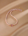 Pearl necklace with a pink gemstone on a beige fabric background