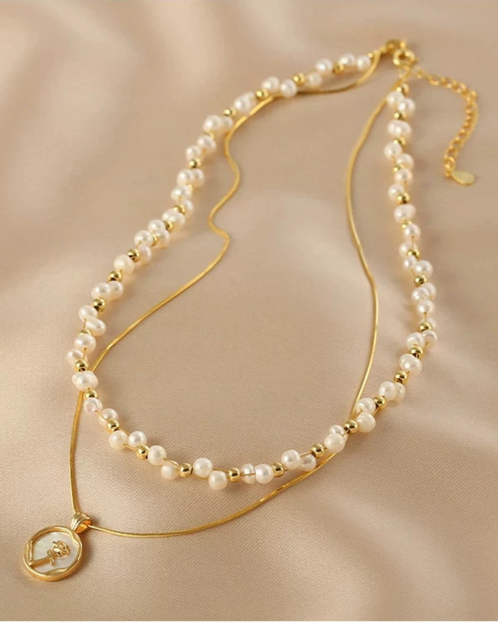 Pearl and gold necklace on a beige fabric background