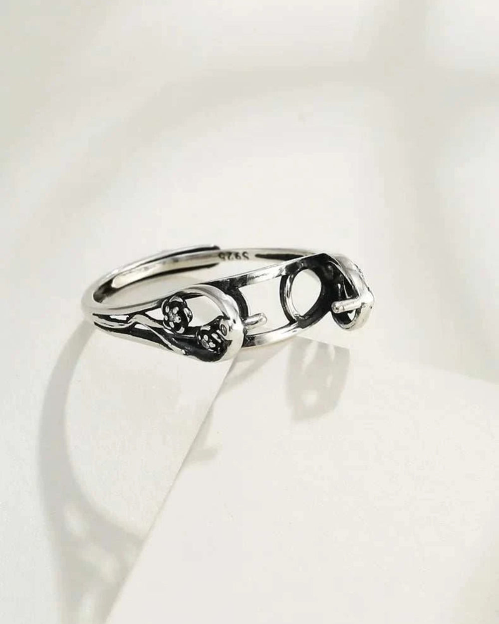 Silver ring with intricate design on a white background