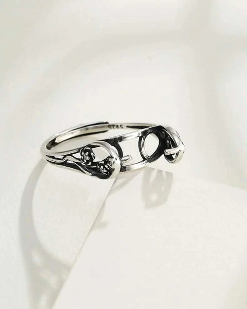 Silver ring with intricate design on a white background