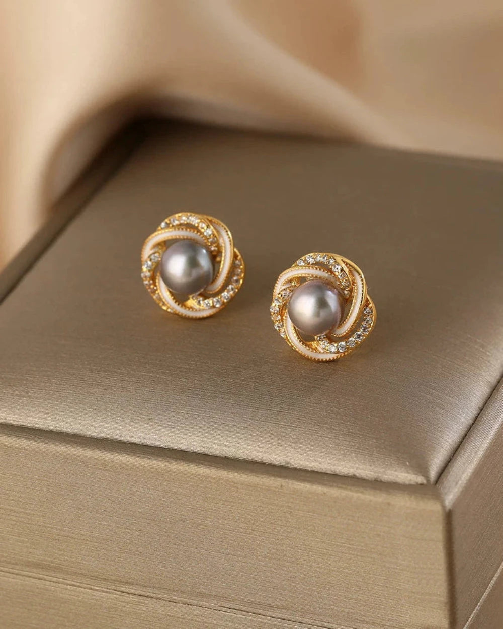 Pair of gold earrings with pearls on a beige surface