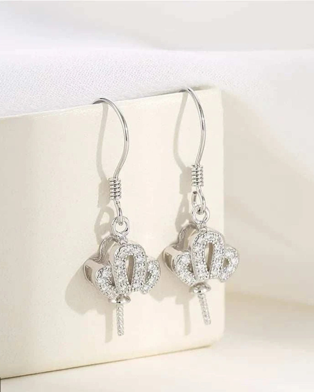 Silver earrings with intricate designs on a white surface