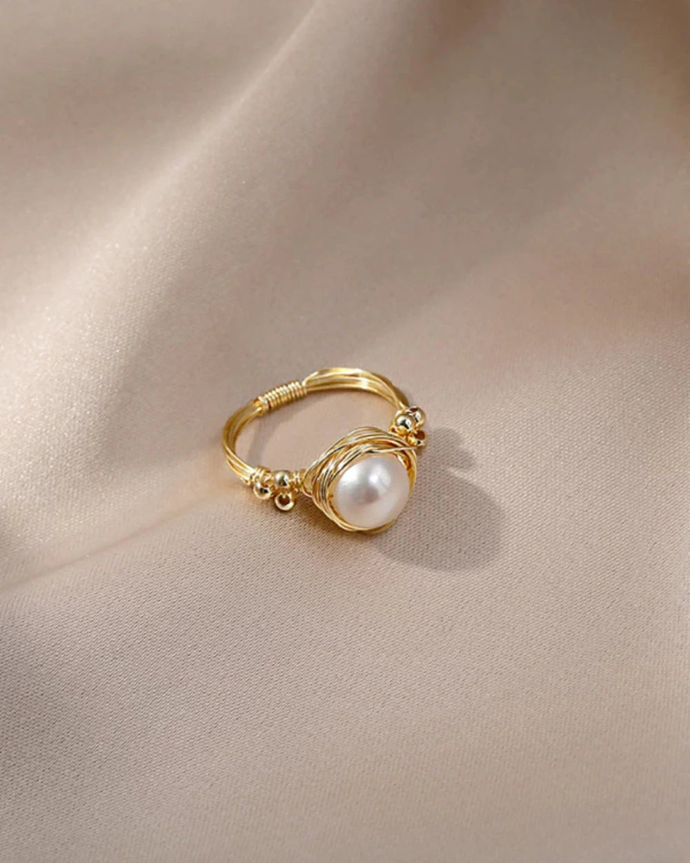 Gold ring with a pearl on a beige fabric background