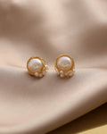 Pearl earrings with gold wire wrapping on a beige fabric background