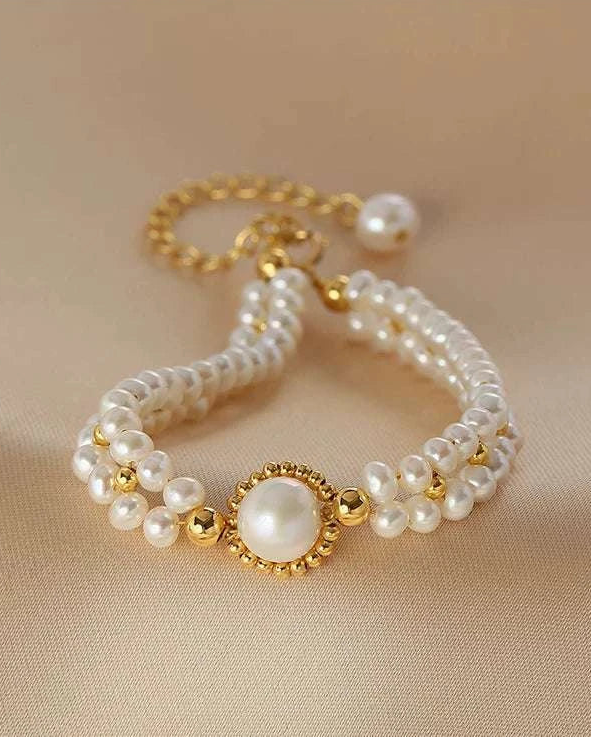 Pearl bracelet with gold accents on a beige fabric background