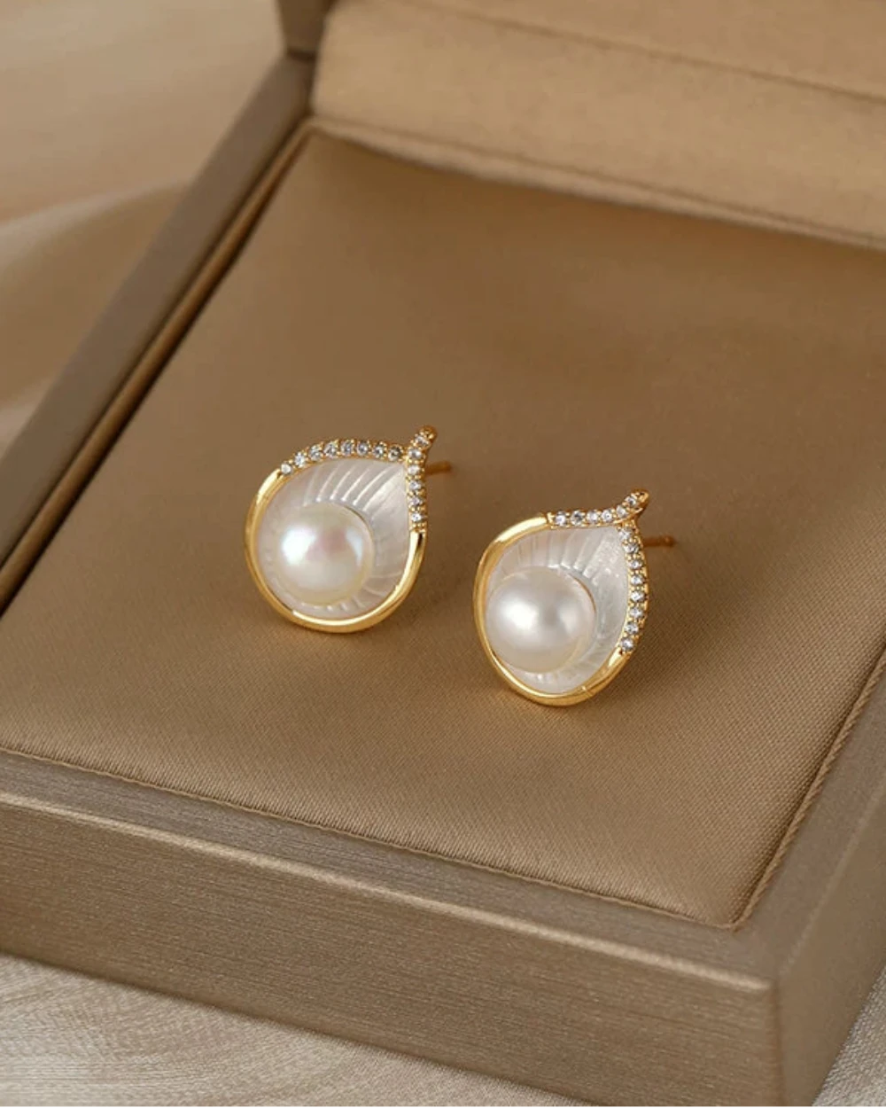 Pearl earrings with gold accents on a beige jewelry box