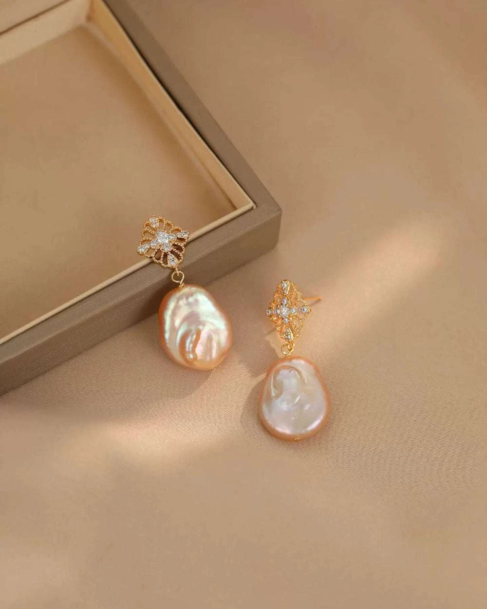 Pearl earrings with gold accents on a beige surface