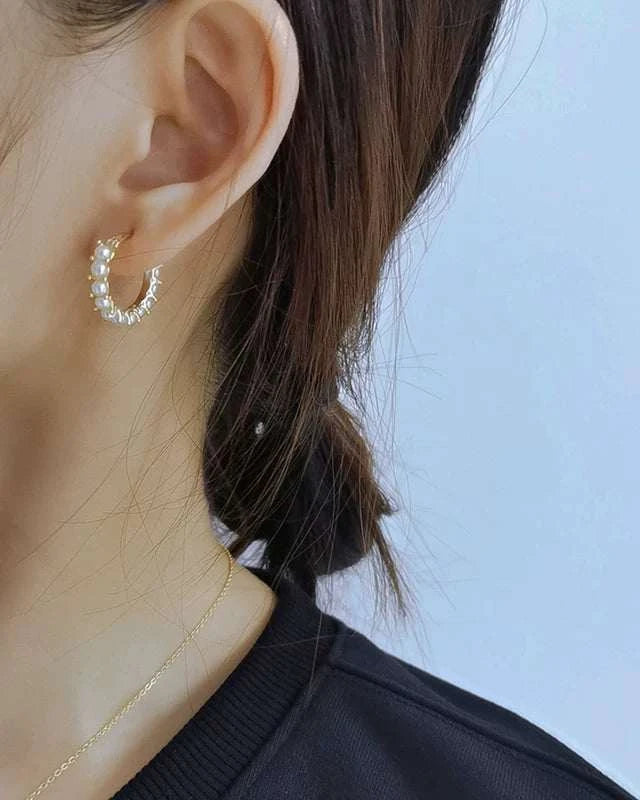 Close-up of a person wearing a small hoop earring with a clear blue sky background