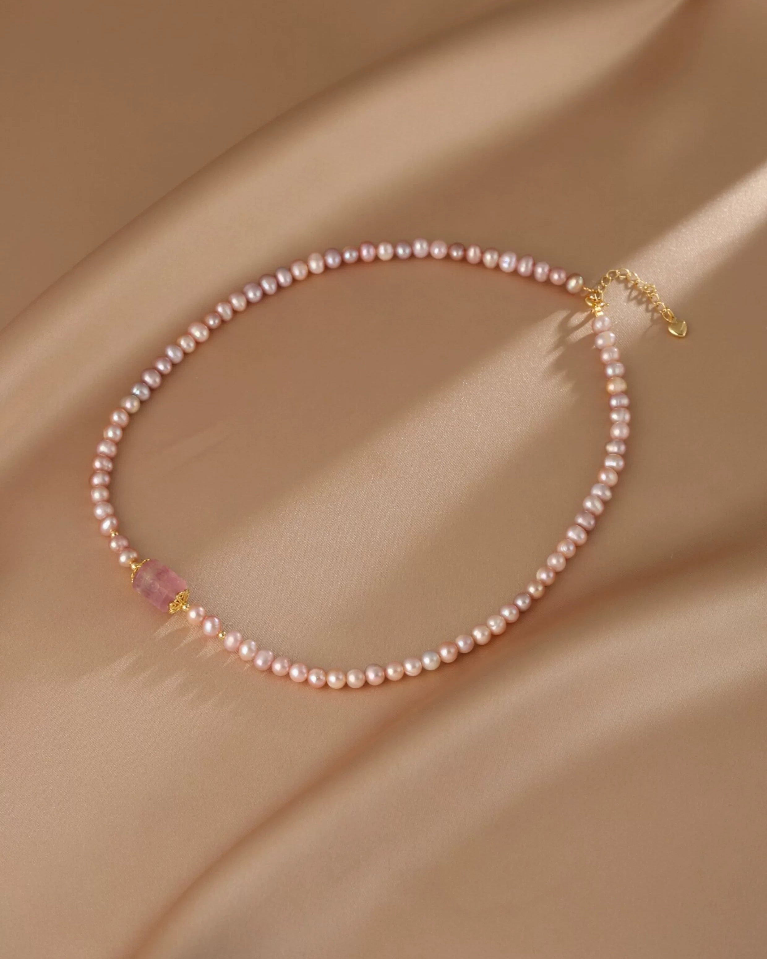 Pearl necklace with gold clasp on a beige fabric background