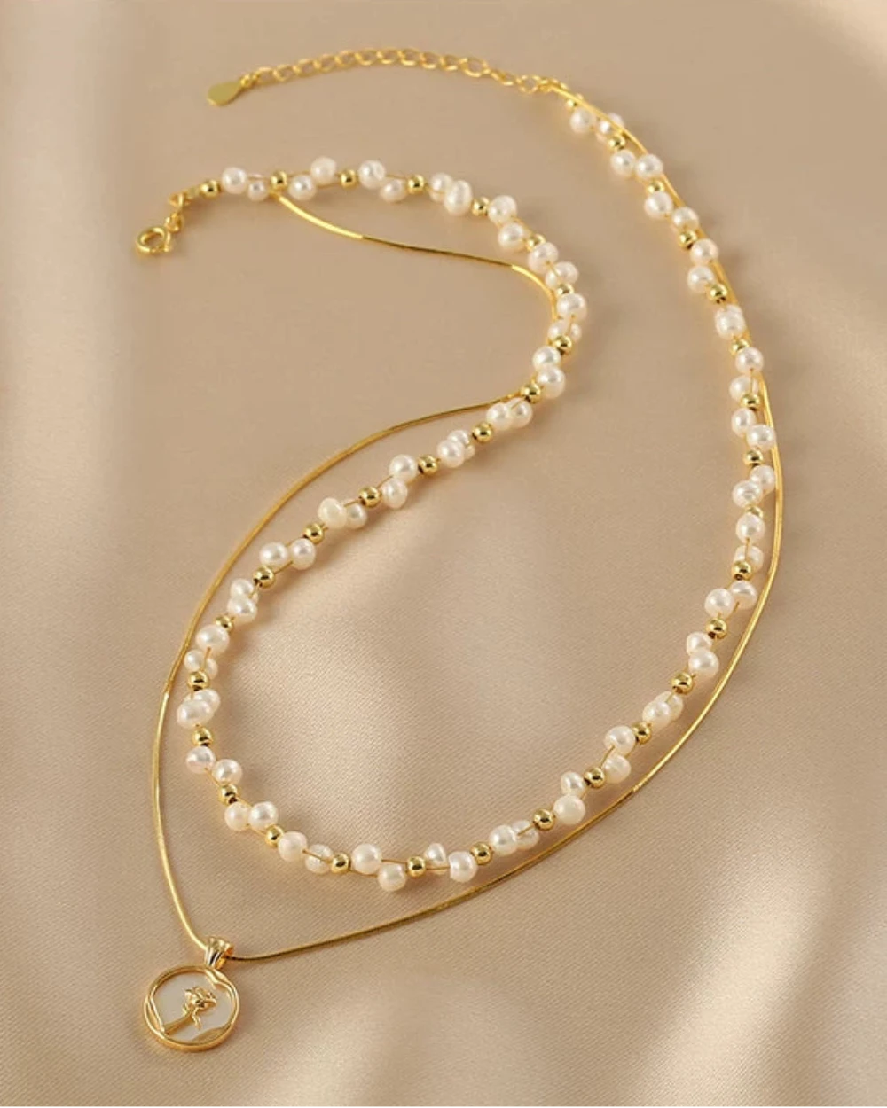 Gold and pearl necklace on a beige fabric background