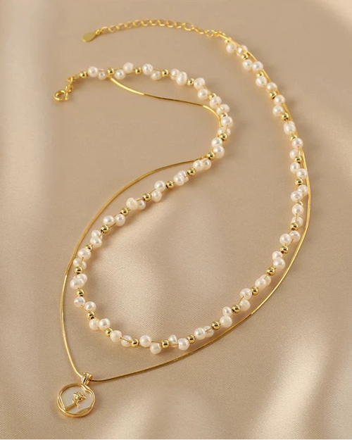 Gold and pearl necklace on a beige fabric background