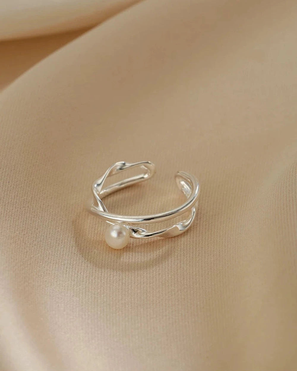Silver ring with a pearl on a beige fabric background