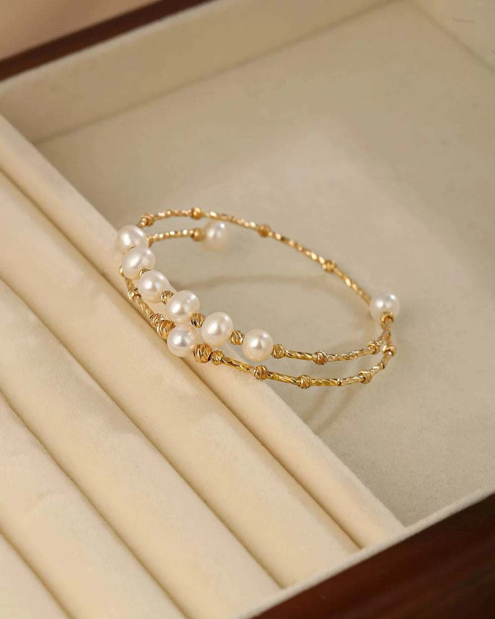 Gold bracelet with pearls on a beige jewelry box