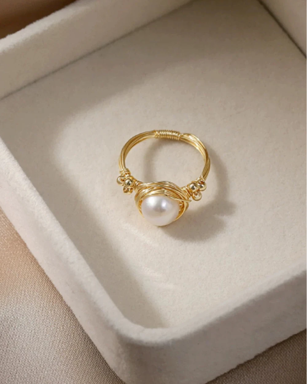 Gold ring with a pearl on a beige jewelry box