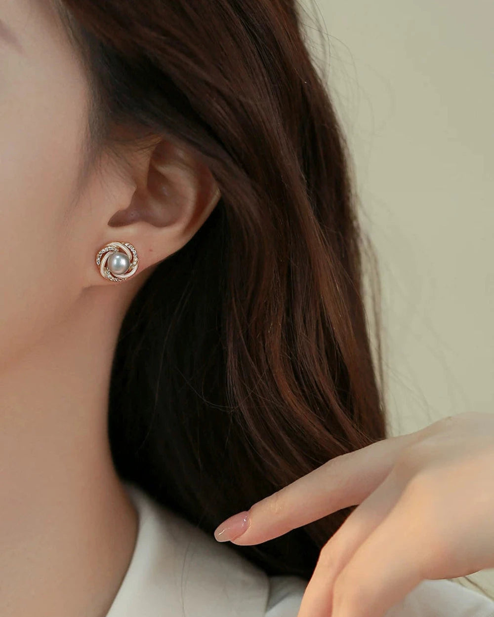 Close-up of a person wearing a pearl earring with a neutral background