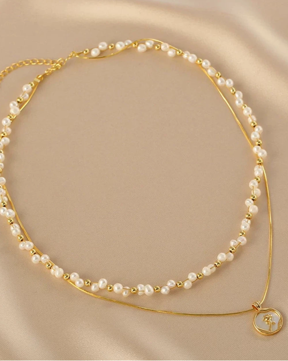 Gold and pearl necklace on a beige background
