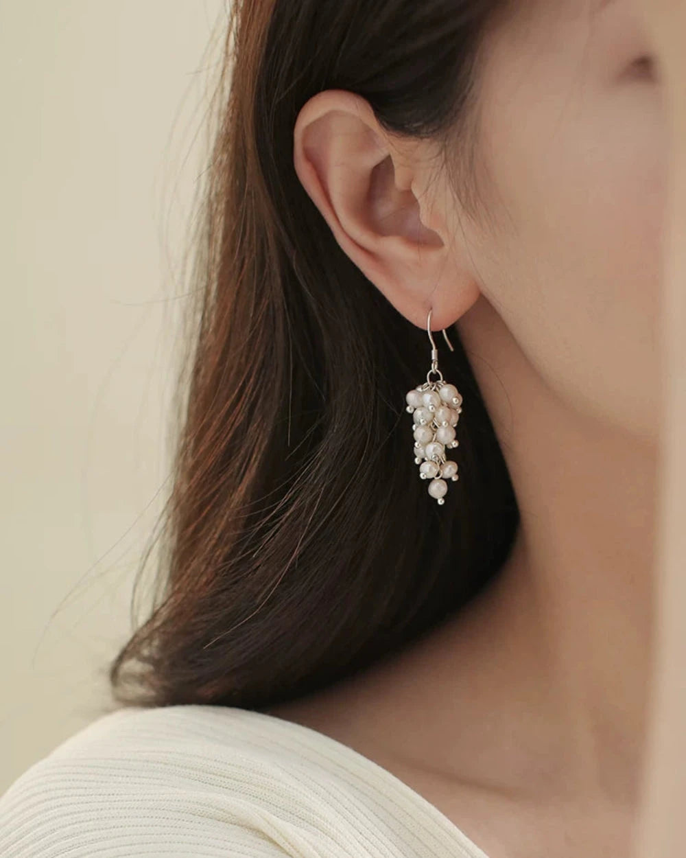 Close-up of a person wearing a delicate silver earring with small stones.
