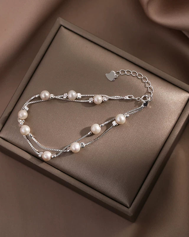 Pearl bracelet on a brown jewelry box with a soft brown fabric background