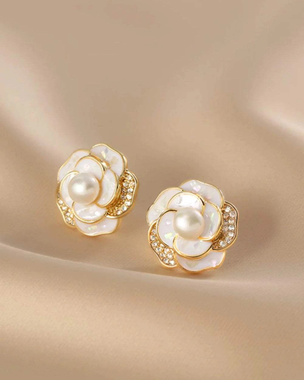 Pair of pearl and gold earrings on a beige background