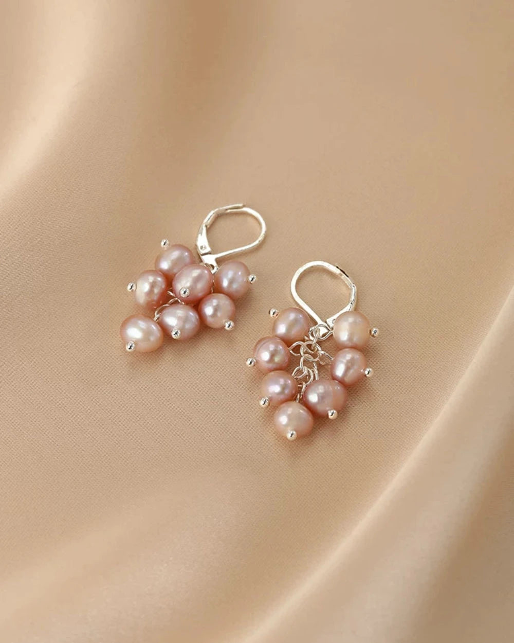 Pair of pearl earrings on a beige fabric background
