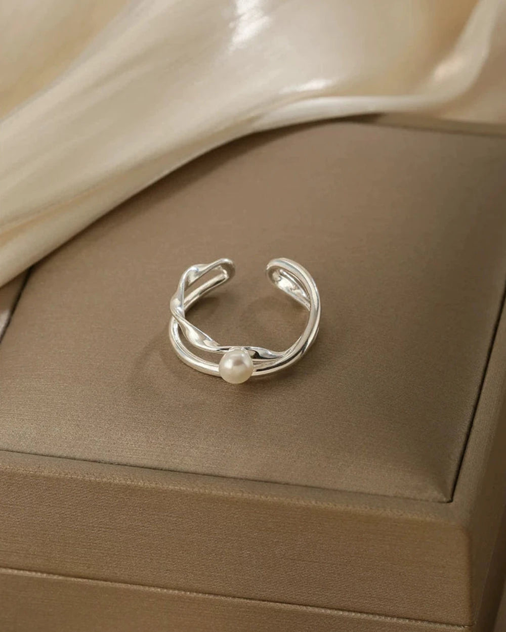 Silver ring with a pearl on a beige jewelry box
