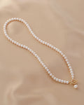 Pearl necklace with a gold clasp on a beige fabric background