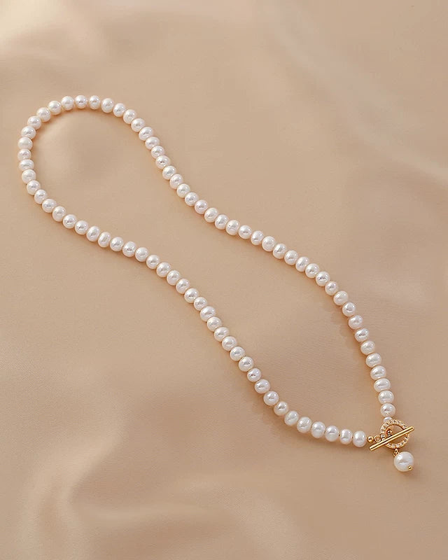 Pearl necklace with a gold clasp on a beige fabric background