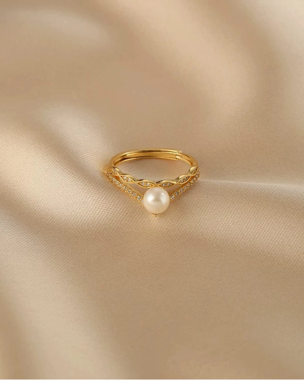 Gold ring with a pearl on a beige fabric background