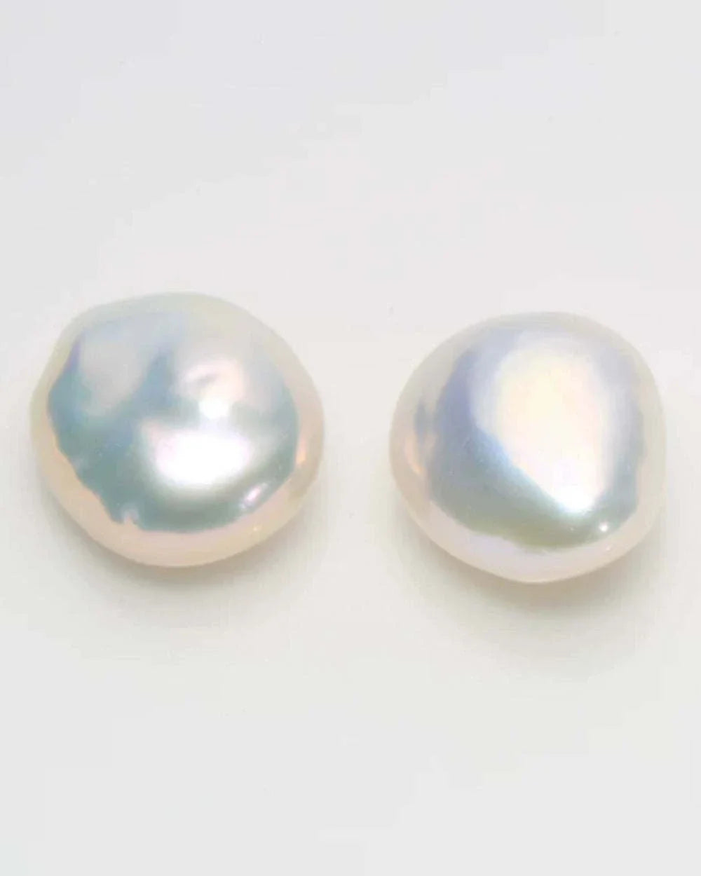 Two pearl earrings on a light gray background