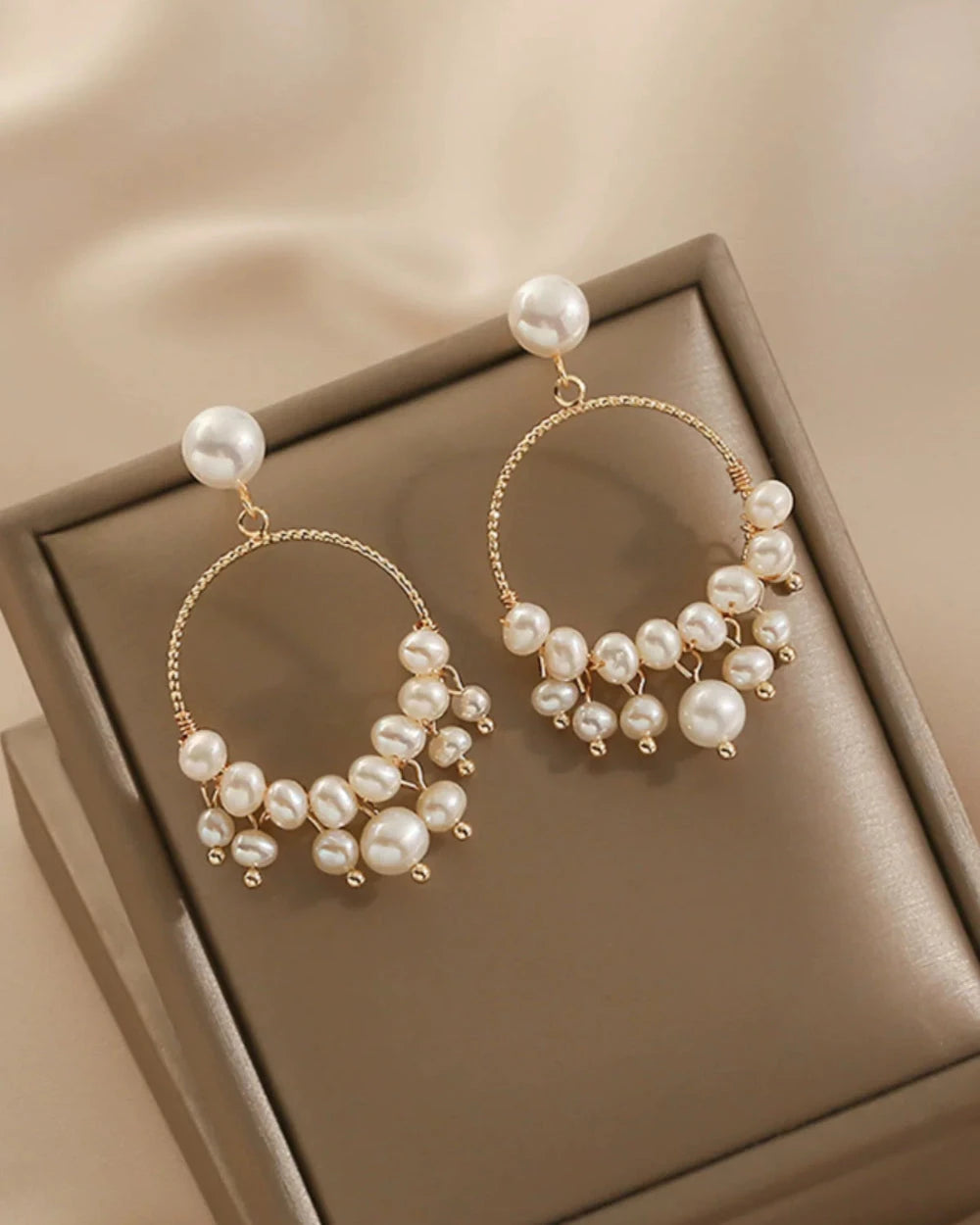 Pearl hoop earrings on a brown jewelry box