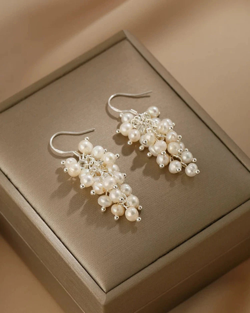 Pearl earrings on a beige jewelry box