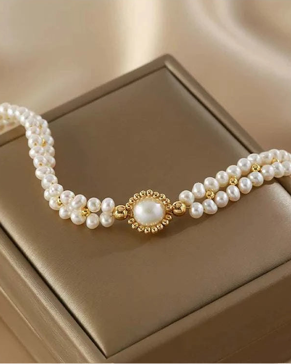 Pearl bracelet with gold accents on a beige jewelry box