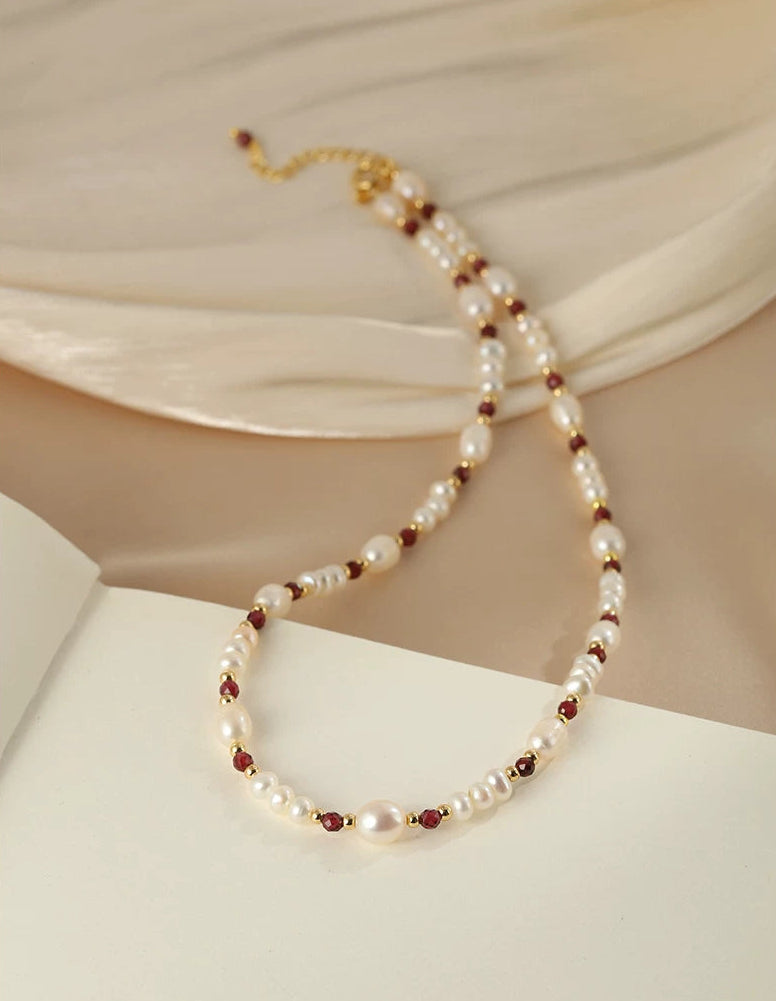 Pearl necklace with red beads on a beige fabric background
